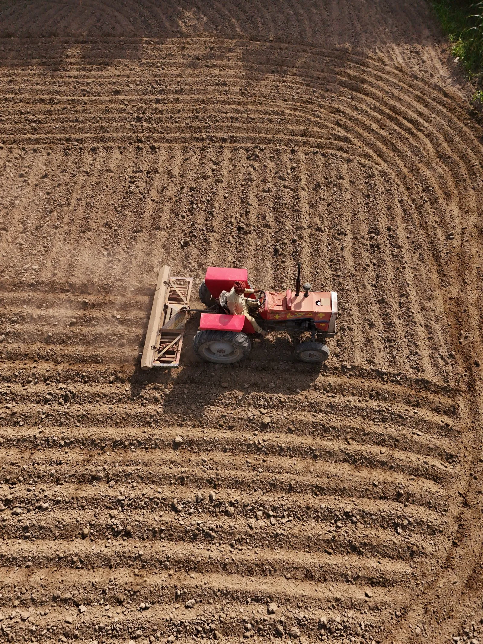 Un trattore in un campo arato, visto dall’alto