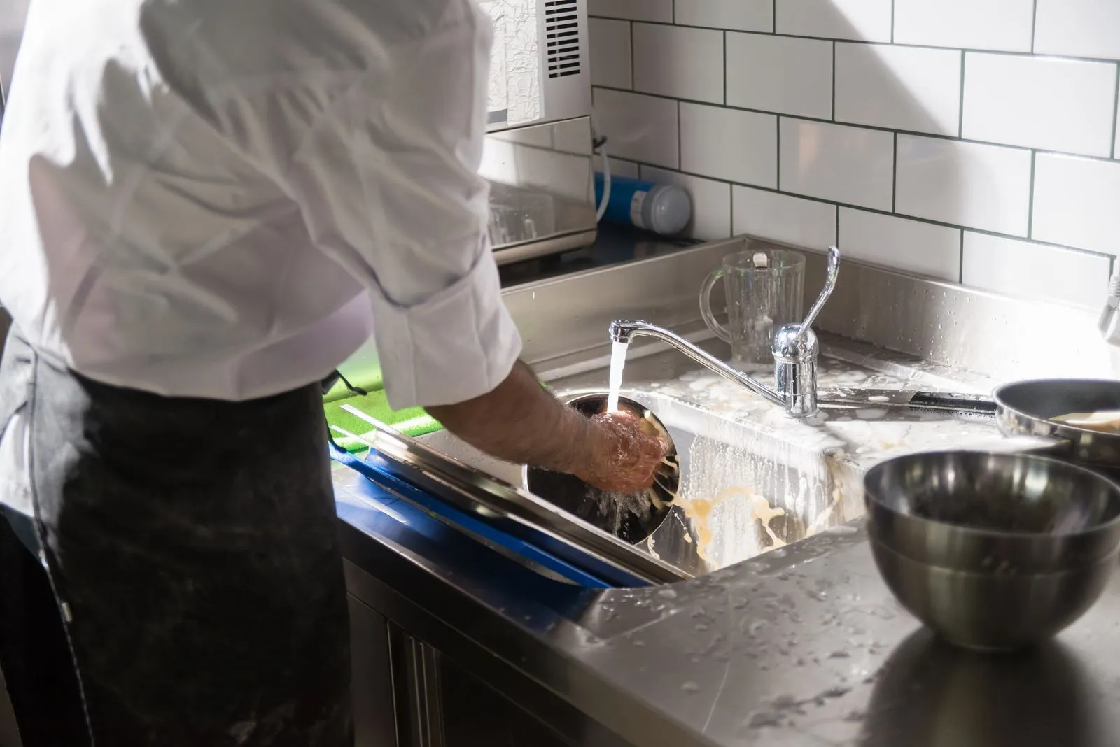 Un cuoco che lava una pentola in una cucina professionale