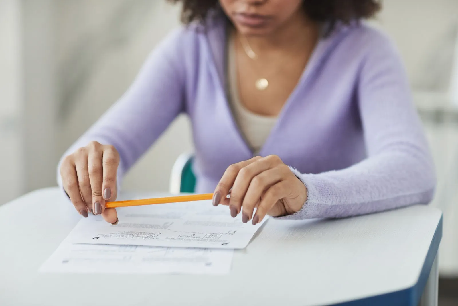 Una ragazza al banco con una matita sopra i fogli di un questionario